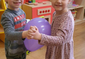 Filip i Nela tańczą z balonem.